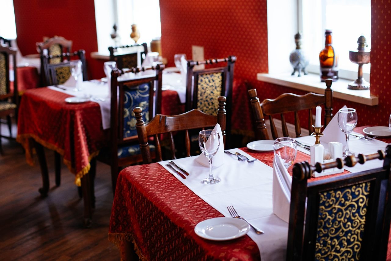 about-us Lavishly set dining tables with elegant cutlery and rich decor in a classic restaurant setting.