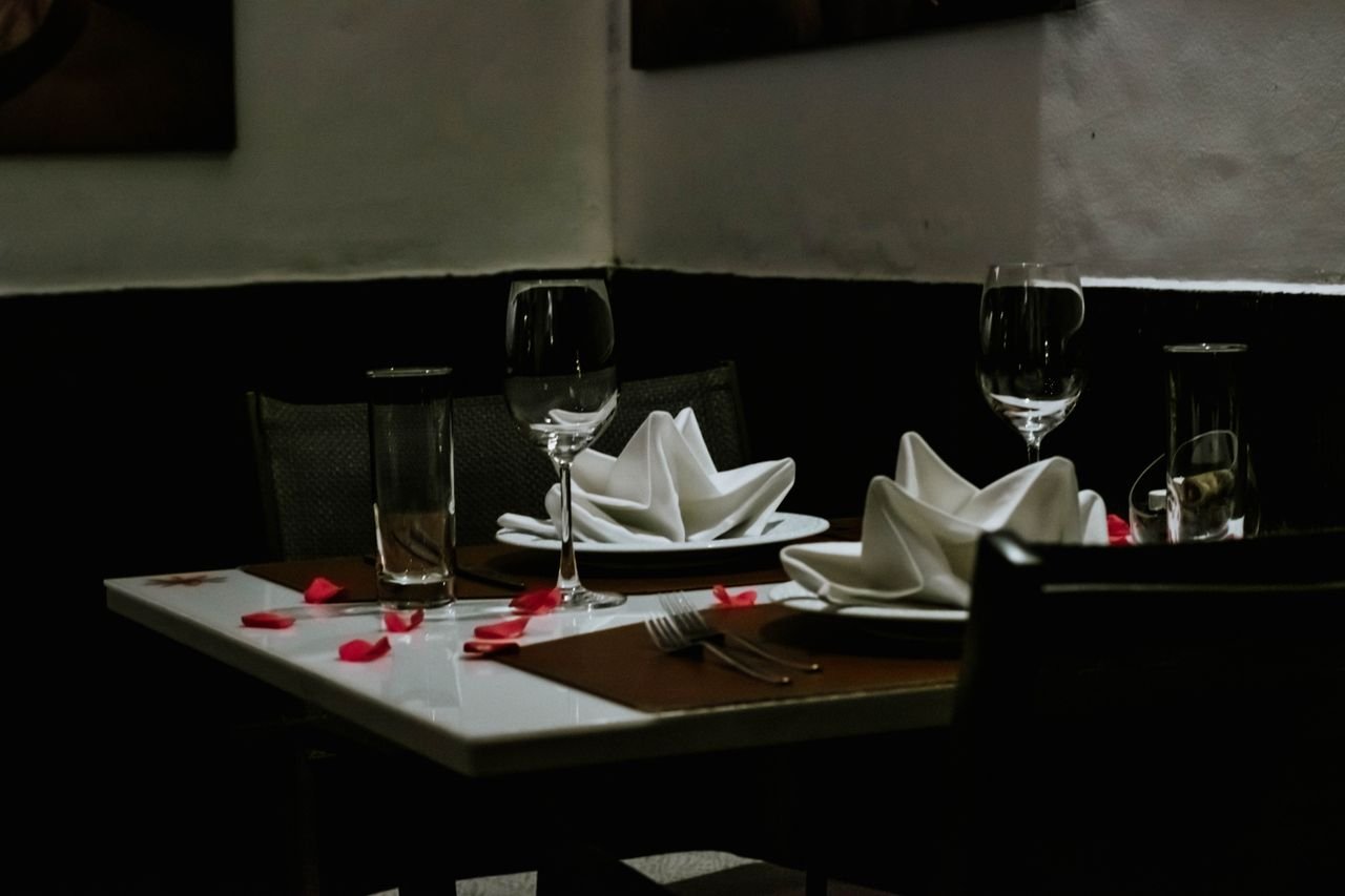 services-02 A romantically set dinner table with napkins and wineglasses, creating a luxurious ambiance indoors.