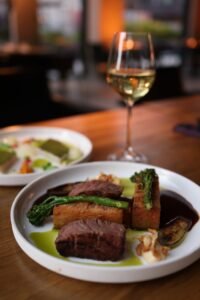 Savoring a gourmet steak dinner with wine in a cozy restaurant setting.