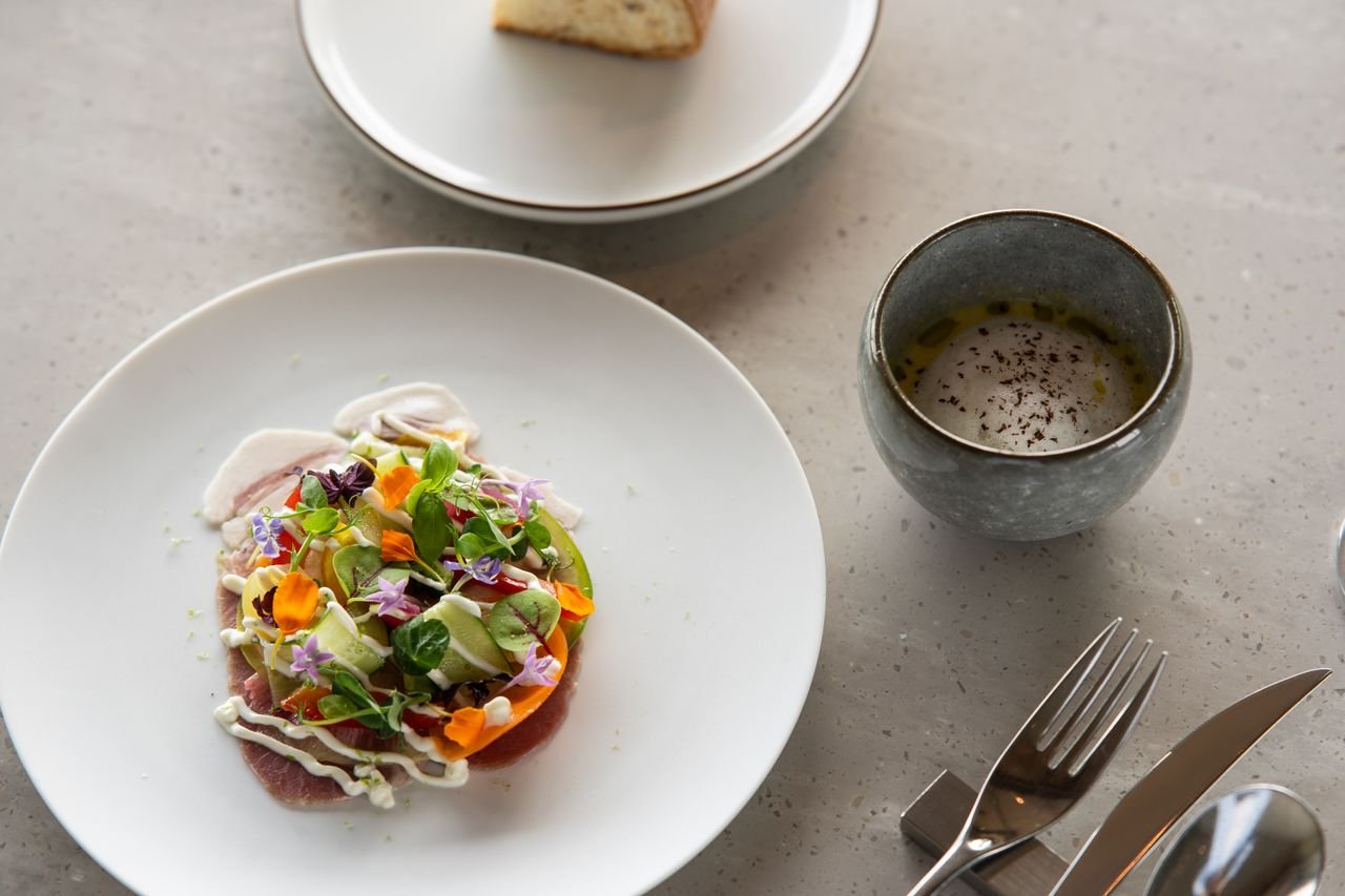 A beautifully presented artisanal salad dish with floral garnishes, set in a sophisticated dining environment.