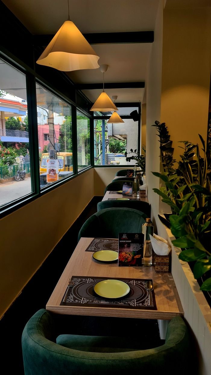 Stylish and cozy restaurant interior with green chairs and window view, perfect for dining.