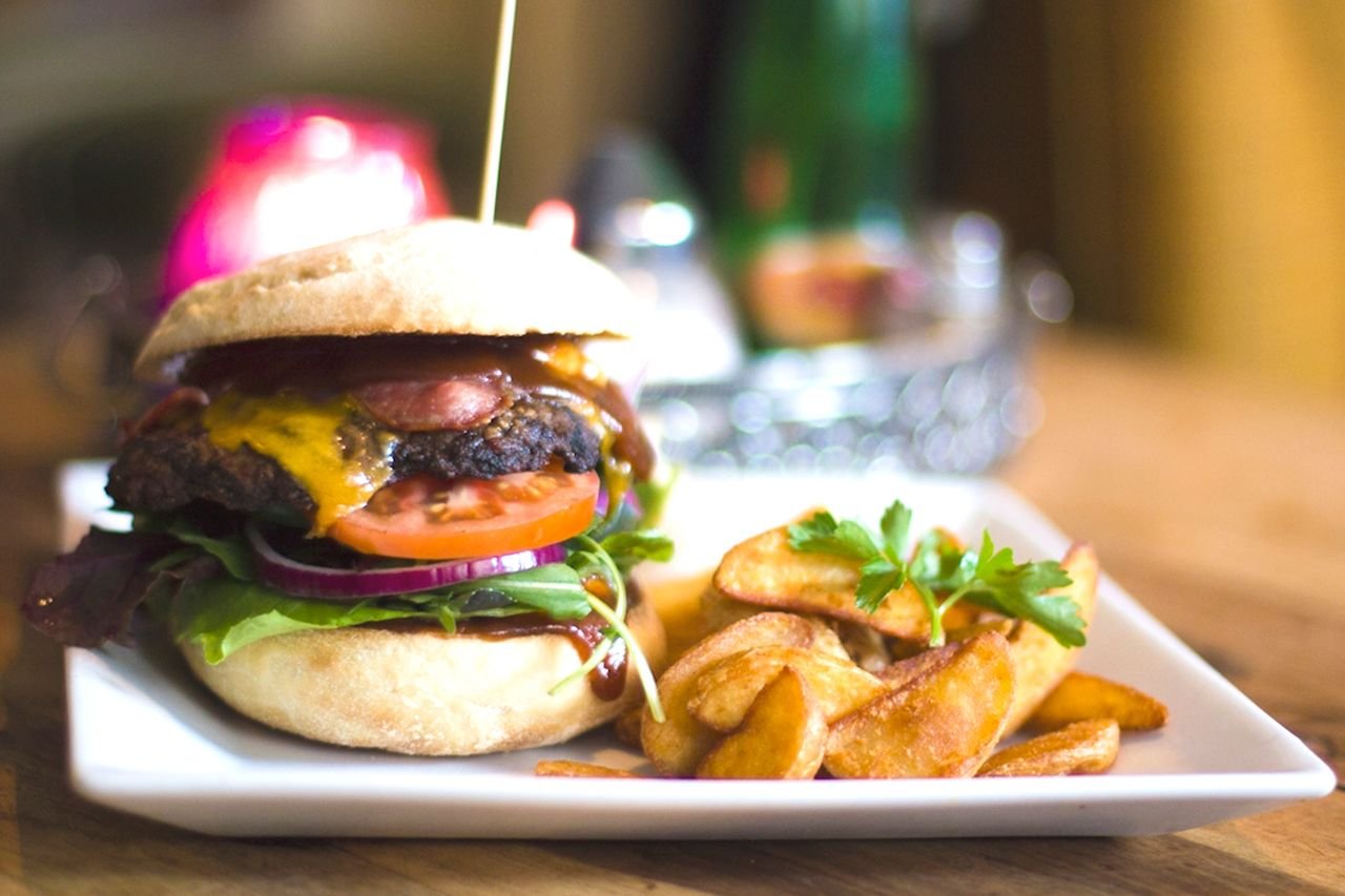 our-story Savor a juicy cheeseburger served with crispy fries on a stylish plate.